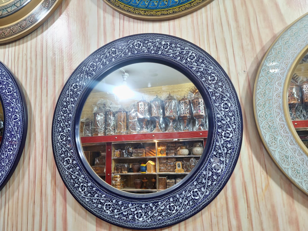 Ornamental circular wall mirror (artisan‑crafted frame).